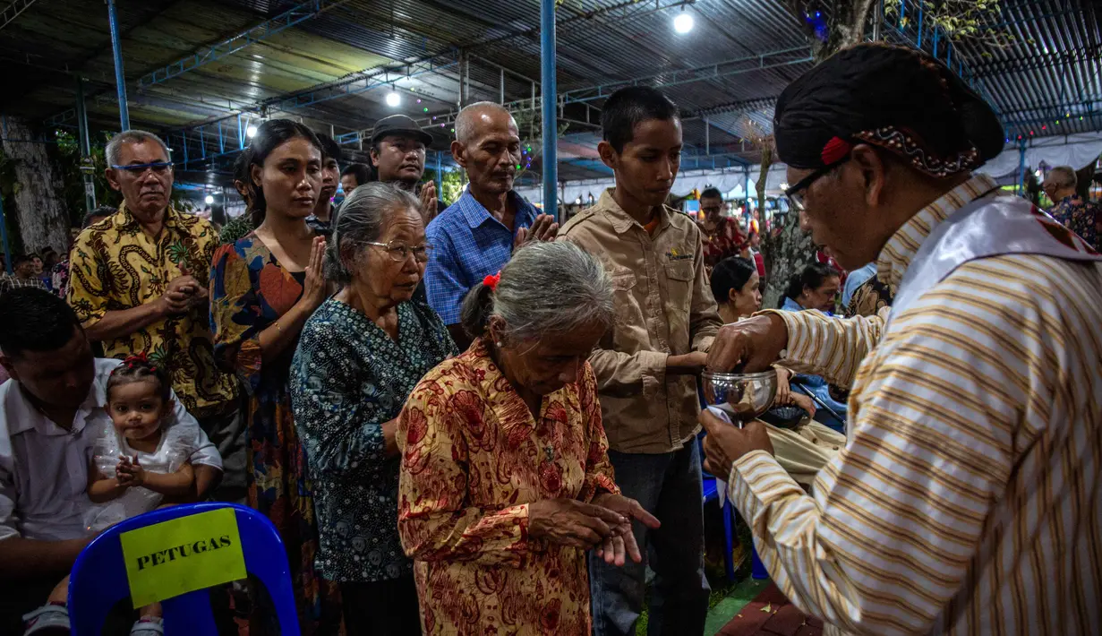 Penggunaan unsur budaya Jawa dalam perayaan keagamaan menjadi ciri khas Gereja Hati Kudus Tuhan Yesus (HKTY) Ganjuran, Bantul, Yogyakarta. Tampak dalam foto, para umat Katolik yang mengenakan pakaian tradisional Jawa menerima Komuni Kudus dari seorang imam selama Misa Malam Natal di Gereja Hati Kudus Yesus di Ganjuran, Bantul, Yogyakarta, pada Rabu 24 Desember 2025. (DEVI RAHMAN/AFP)