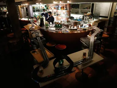 Pekerja menyiapkan minuman setelah mereka memasang lintasan mobil balap mainan di sebuah bar di Praha, Republik Ceko, 15 Oktober 2020. Area bar menjadi lintasan mobil mainan yang bisa dimanfaatkan para karyawan untuk mengusir kebosanan saat menunggu pesanan. (AP Photo/Petr David Josek)