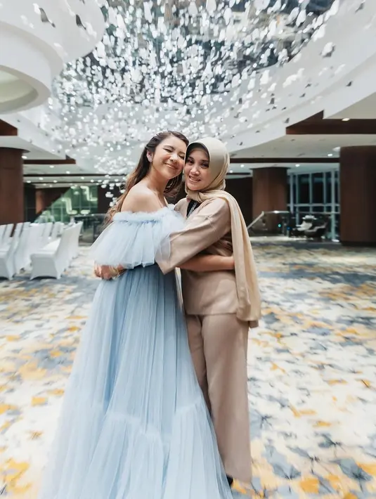 Berpose mesra dengan sang ibunda, Tiara Andini tampil bak princess dalam balutan gaun yang cantik. Off-the-shoulder gown berwarna baby blue ini memiliki detail cape di bagian dada, jatuh ke bawah dengan kesan flowy yang anggun. Foto: Instagram.