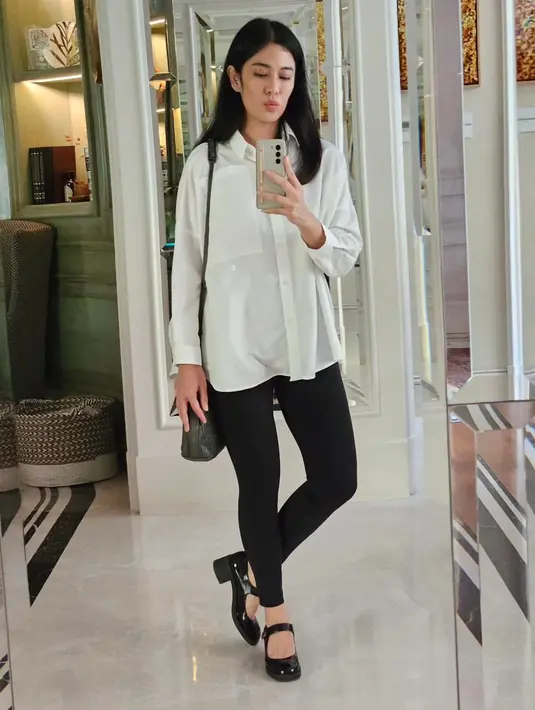 Dian Satrowardoyo tampil chic yang juga bisa kamu jadikan inspirasi tampil di acara bukber. Ia mengenakan oversized shirt berwarna putih, dipadukannya dengan celana legging hitam. [Foto: Instagram/therealdisastr]