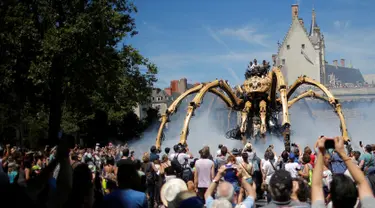 Sejumlah orang melihat robot mekanik laba-laba raksasa bernama Kumo Ni saat berjalan berkeliling Kota Nantes, Prancis, Jumat (8/7). Robot Mekanik laba-laba raksasa ini di buat oleh perusahaan La Machine. (REUTERS/Stephane Mahe)