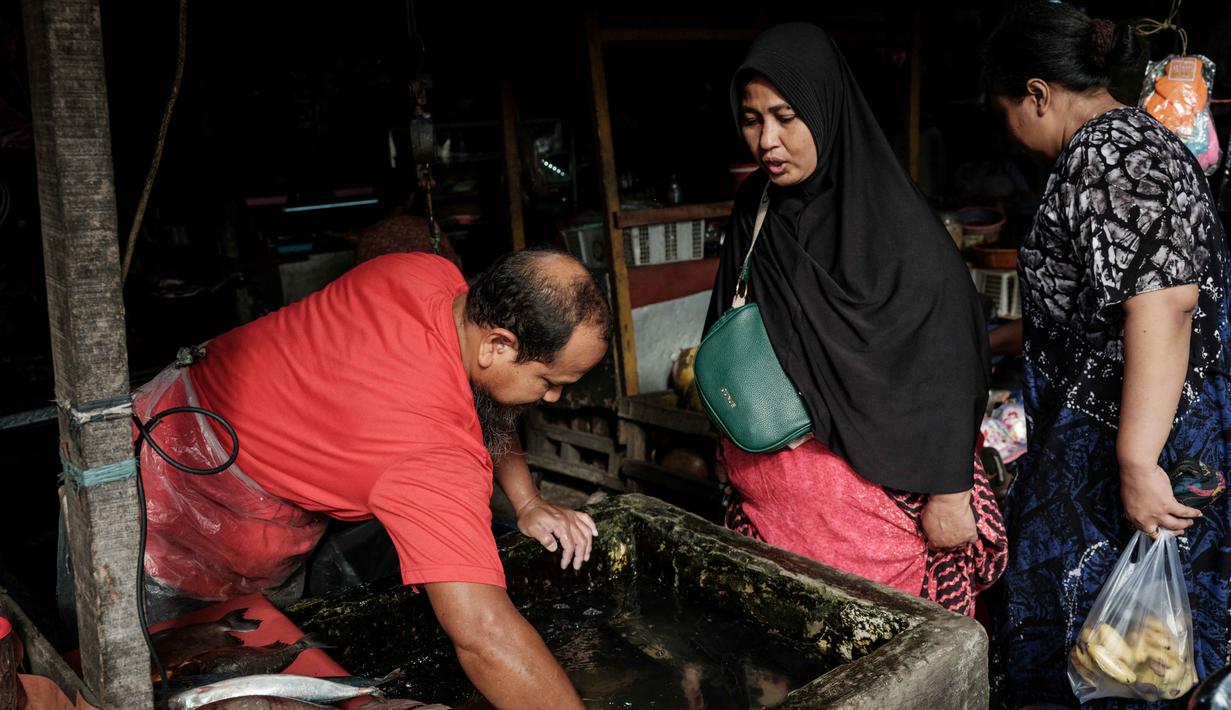 Guna menjaga momentum tersebut, pemerintah akan mengandalkan stimulus fiskal dan pembiayaan sektor riil. Tampak dalam foto, seorang penjual ikan memasukkan tangannya ke dalam tangki untuk menangkap ikan bagi seorang pelanggan di sebuah kios pinggir jalan di Jakarta pada Sabtu 8 November 2025. (YASUYOSHI CHIBA/AFP)