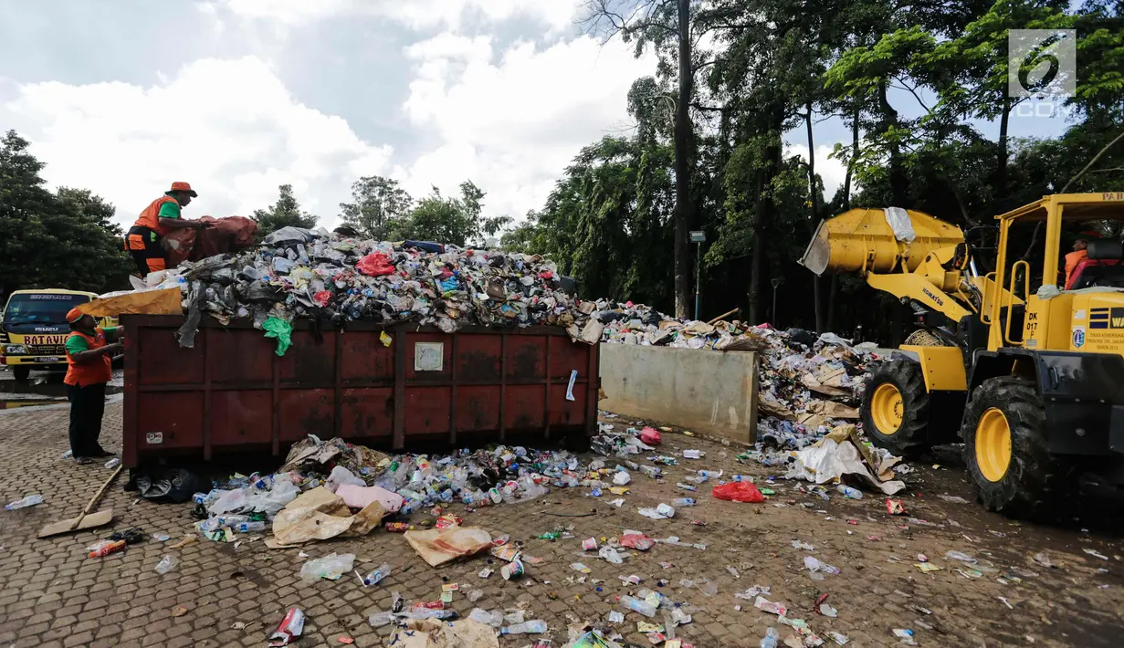 Petugas kebersihan dibantu alat berat membersihkan sampah Tahun Baru 2018 di Monas, Jakarta, Senin (1/1). Setelah perayaan malam tahun baru 2018, sampah sisa pengunjung berserakan di lokasi perayaan. (Liputan6.com/Faizal Fanani)
