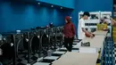 Diketahui, masih tersisa sekitar Rp 50 triliun plafon KUR yang siap disalurkan hingga akhir tahun untuk mendorong aktivitas Usaha Mikro, Kecil, dan Menengah (UMKM). Tampak dalam foto, warga menggunakan jasa layanan laundry pinggir jalan di Jakarta pada Sabtu 8 November 2025. (YASUYOSHI CHIBA/AFP)