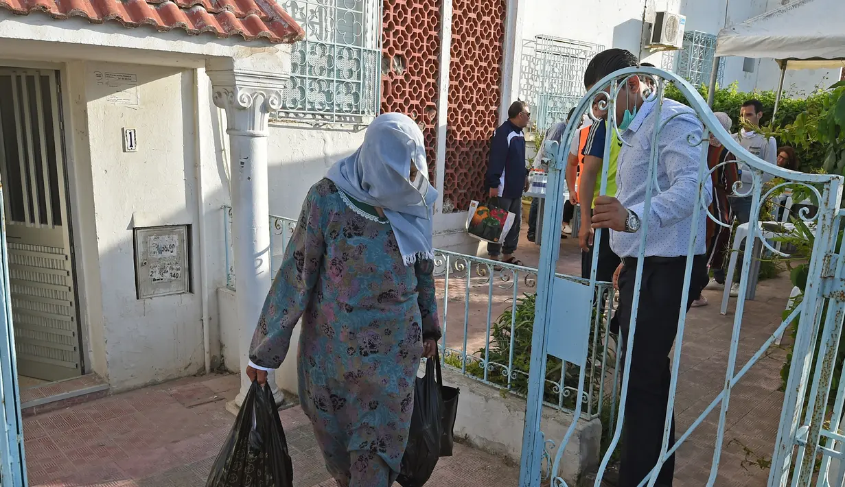 Warga membawa makanan berbuka puasa gratis dari relawan selama bulan suci Ramadan di Ariana, Tunisia (7/5/2020). Masjid-masjid di Aljazair, Maroko dan Tunisia telah ditutup untuk membatasi penyebaran Covid-19, mencegah doa malam khusus. (AFP/Fethi Belad)