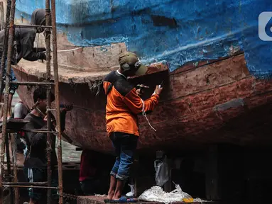 Buruh melakukan perbaikan kapal nelayan di Galangan kapal, Muara Angke, Jakarta, Minggu (23/12/2020). Dimasa pandemi Covid 19 aktivitas di galangan kapal tetap berjalan normal seperti biasa. (Liputan6.com/Angga Yuniar)