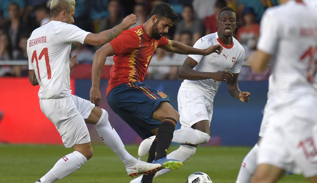 Striker Spanyol, Diego Costa, berusaha melewati gelandang Swiss, Valon Berhami, pada laga persahabatan di Stadion La Ceramica, Vila-real, Minggu (3/6/2018). Kedua negara bermain imbang 1-1. (AFP/Jose Jordan)