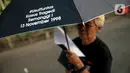 Anggota Jaringan Solidaritas Korban untuk Keadilan (JSKK) menggunakan payung hitam bertuliskan #UsutTuntas "Kasus Tragedi Semanggi I 13 November 1998 saat melakukan Aksi Kamisan ke-795 di seberang Istana Merdeka, Jakarta, Kamis (16/11/2023). (Liputan6.com/Faizal Fanani)