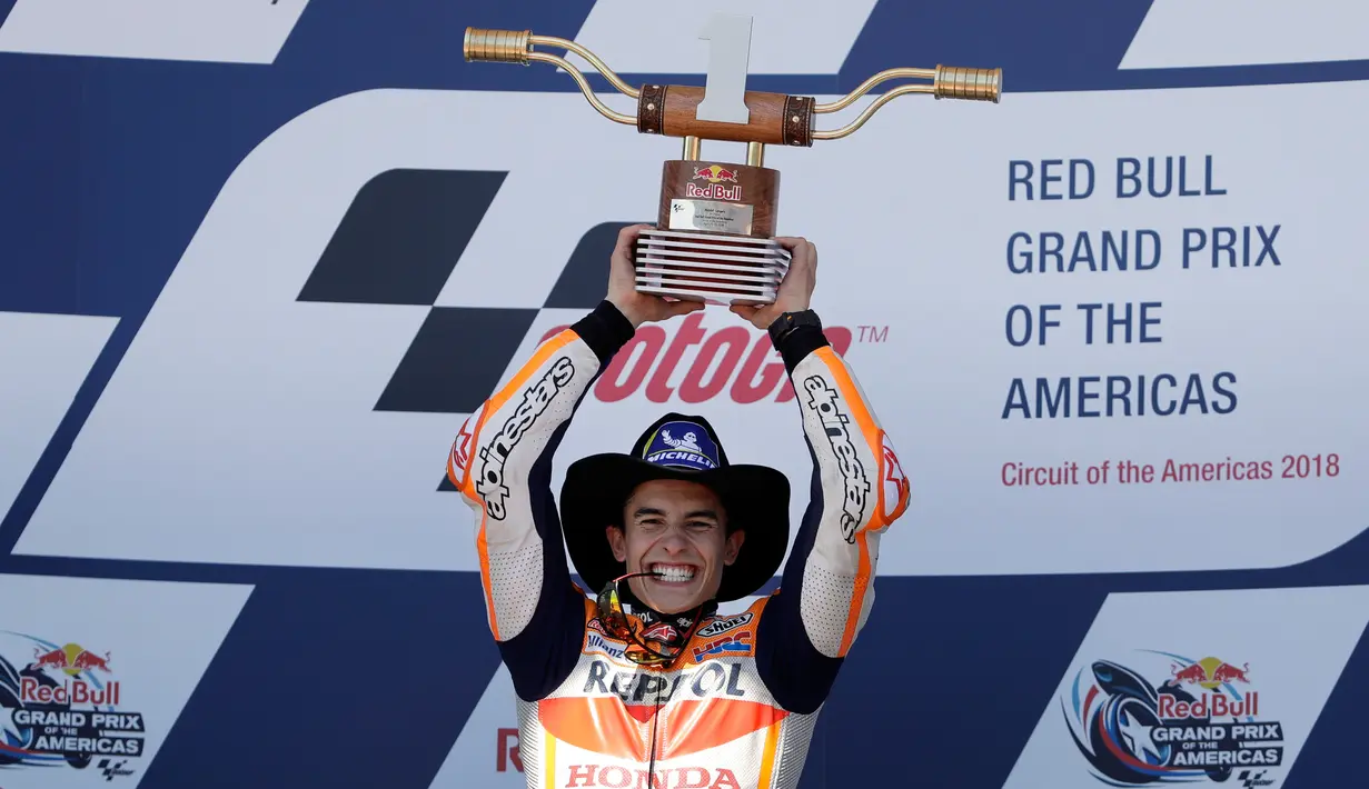 Pembalap Repsol Honda, Marc Marquez mengangkat trofi juara MotoGP Spanyol 2018 di Sirkuit Jerez, Minggu (6/5). Kemenangan ini jadi kedua beruntun bagi Marquez setelah dua pekan lalu juga jadi kampiun pada MotoGP AS. (AP Photo/Miguel Morenatti)