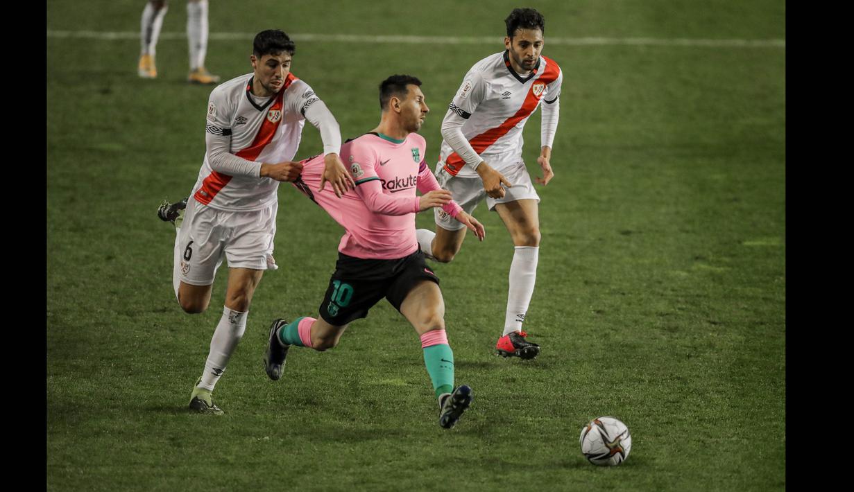 Pemain Rayo Vallecano, Santiago Comensano menarik baju pemain Barcelona, Lionel Messi pada laga babak 16 Besar Copa del Rey di Vallecas stadium, Madrid, Kamis (28/1/2021). (Foto: AP/Manu Fernandez)