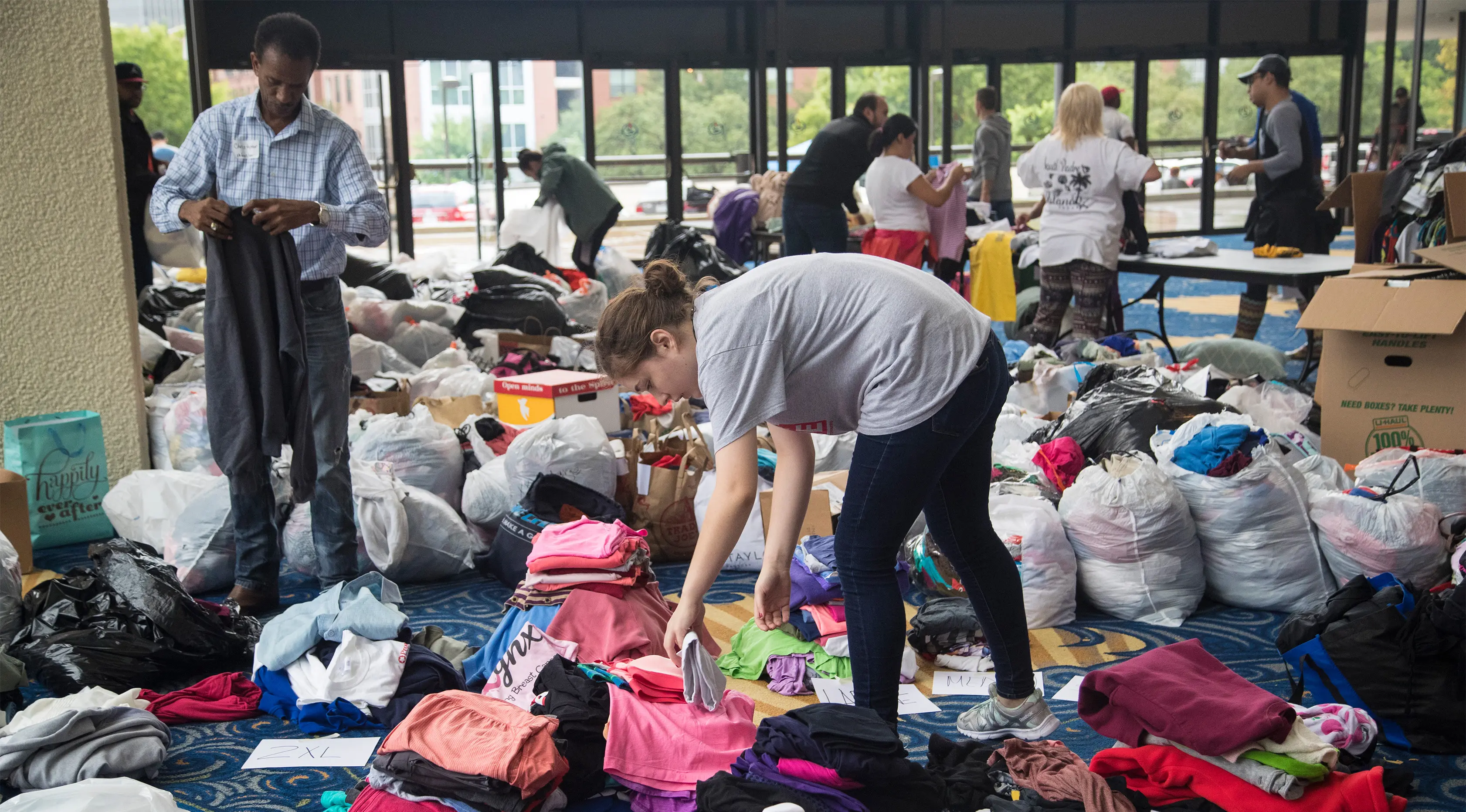 Seorang relawan memilah baju hasil donasi sebelum dibagikan kepada korban Harvey di Houston, Selasa (29/8). Puluhan badan amal terpercaya lainnya turut membantu aksi penggalangan dana untuk korban Harvey. (Marie D. De Jesus/Houston Chronicle via AP)