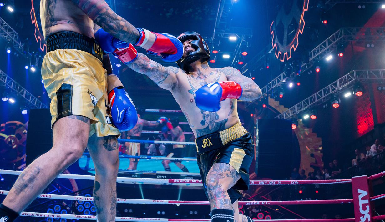 Pemain drum Superman is Dead, Jerinx (kanan), melakukan pukulan kearah perut dari Komika, Uus, dalam pertandingan tinju Holywings Sport Show (HSS) Series 3 yang berlangsung di Atlas Super Club, Bali, Minggu (10/9/2023). (Dok. Holywings)