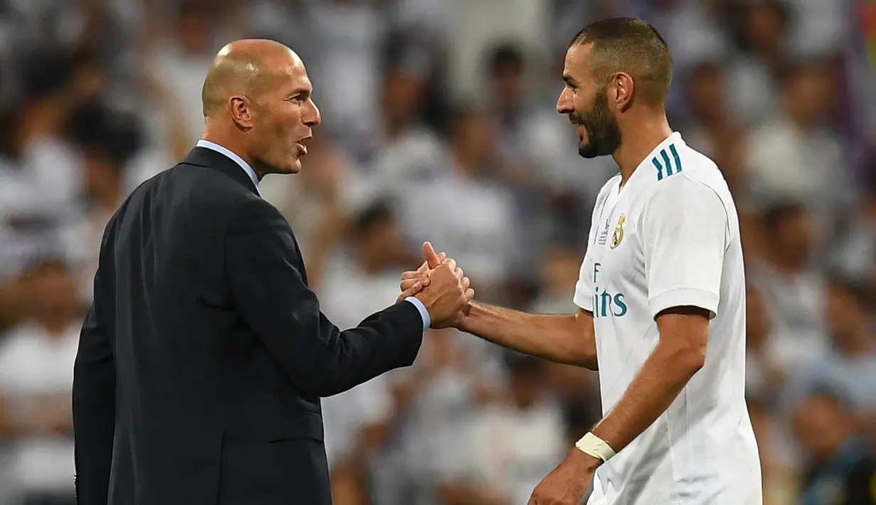 Pelatih Real Madrid, Zinedine Zidane (kiri) bersalaman dengan Karim Benzema merayakan kemenagan atas Barcelona pada Piala Super Spanyol 2017 usai pertandingan melawan Barcelona di stadion Santiago Bernabeu, Spanyol (16/8). (AFP Photo/Gabriel Bouys)