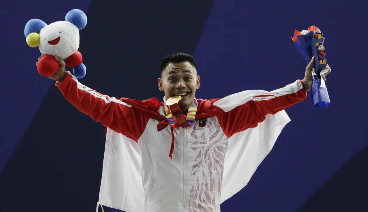 Lifter Eko Yuli melakukan selebrasi saat mendapatkan medali emas SEA Games 2019 cabang angkat besi nomor 61 kg di Stadion Rizal Memorial, Manila, Minggu (1/12). Dirinya meraih emas dengan total angkatan 309 kg. (Bola.com/M Iqbal Ichsan)