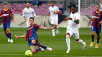 Gelandang Barcelona Sergio Busquets dan penyerang Real Madrid, Vinicius Junior berebut bola pada laga La Liga bertajuk El Clasico di Nou Camp, Sabtu (24/10/2020). Barcelona harus menelan pil pahit kalah 1-3 dari musuh bebuyutannya Real Madrid di kandang sendiri, Nou Camp. (AP Photo/Joan Monfort)