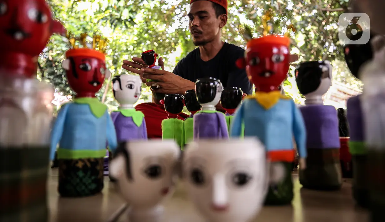 Chairuddin (40) bersama rekannya menyelesaikan pembuatan ondel-ondel dari botol bekas di Sanggar Rumah Kreasi, Jakarta, Minggu (13/6/2021). Botol bekas dimanfaatkan menjadi ondel-ondel untuk dijual dengan harga sepasang Rp35 ribu dan bisa membuat ratusan setiap harinya. (Liputan6.com/Johan Tallo)