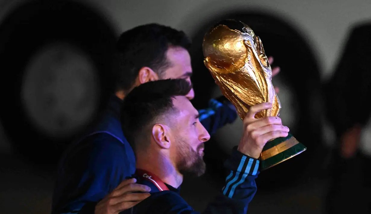 Kapten Argentina Lionel Messi (kiri) memegang Trofi Piala Dunia 2022 bersama pelatih Lionel Scaloni setibanya di Bandara Internasional Ezeiza di Ezeiza, provinsi Buenos Aires, Argentina (20/12/2022). Ini adalah gelar juara Piala Dunia ketiga dalam sejarahnya. Terakhir kali Argentina juara pada 1986 alias 36 tahun lalu. Argentina yang diperkuat Diego Maradona mengandaskan Jerman Barat 3-2 dalam final Piala Dunia di Meksiko. (AFP/Luis Robayo)