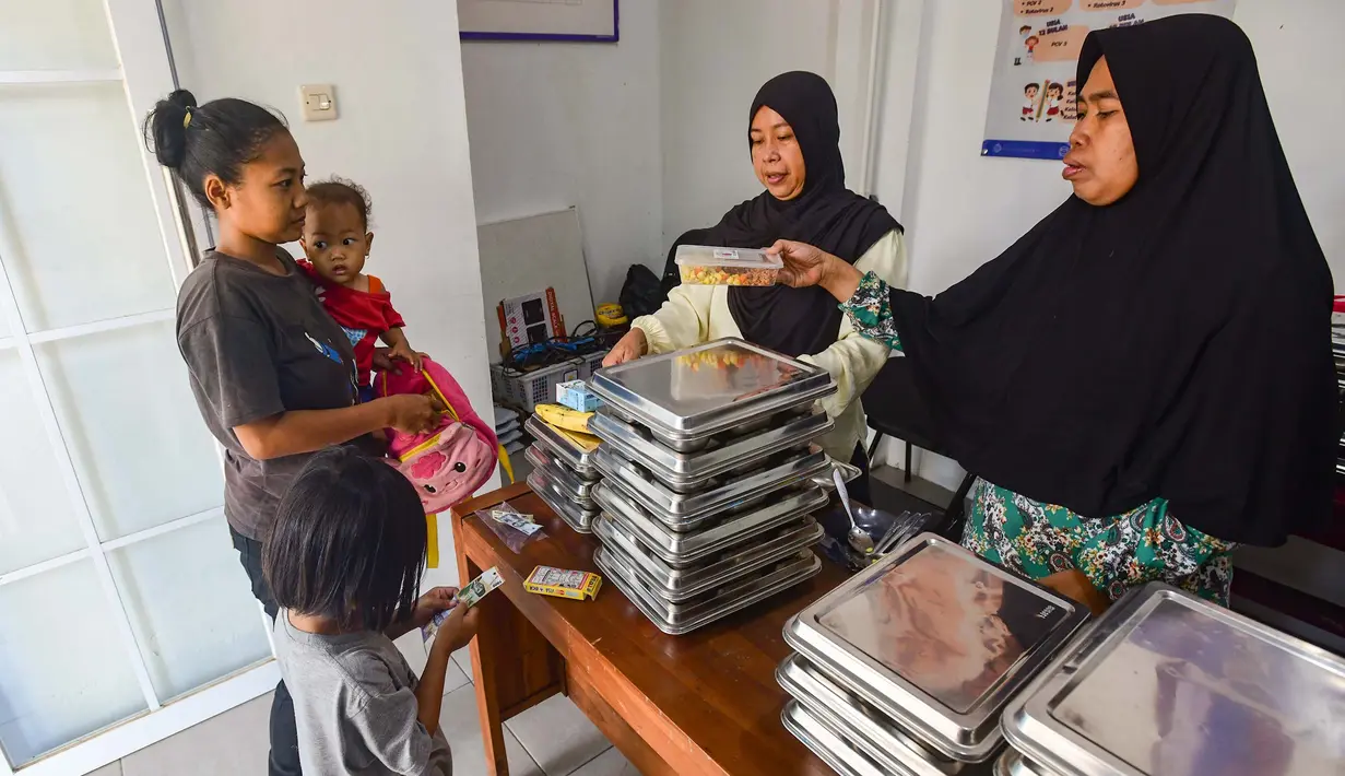 Ibu dan anaknya mengambil makan bergizi gratis (MBG) untuk dikonsumsi di rumah di Posyandu kawasan Limo, Depok, Jawa Barat, Selasa (14/7/2025).
