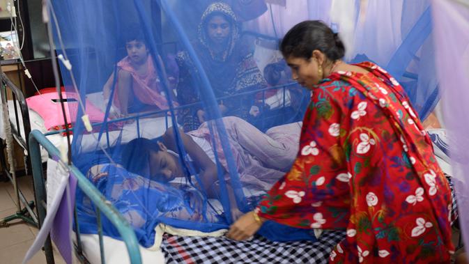 Seorang wanita merapikan tempat tidur anaknya yang menjadi pasien demam berdarah di Rumah Sakit Shishu Dhaka, Bangladesh, Rabu (31/7/2019). Banyak rumah sakit dibanjiri pasien penyakit itu sehingga semakin membebani sistem layanan medis yang saat ini sudah kewalahan. (AP Photo/Mahmud Hossain Opu)