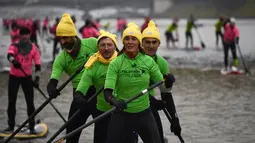 Presenter televisi Prancis Nathalie Simon dan timnya ambil bagian pada perlombaan dayung sambil berdiri Nautic SUP Paris di sungai Seine, Minggu (3/12). Nautic SUP Paris merupakan lomba dayung sambil berdiri terbesar di dunia. (AFP PHOTO/CHRISTOPHE SIMON)