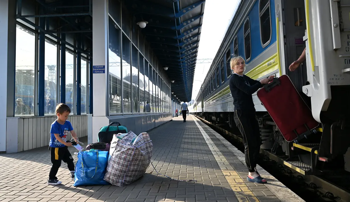 <p>Seorang ibu dan anaknya, salah satu dari ribuan perempuan dan anak-anak yang melarikan diri dari Ukraina setelah Rusia menginvasi, turun dengan barang bawaannya setibanya mereka dari Polandia, di stasiun kereta api Kiev pada 12 Mei 2022. Untuk pertama kalinya sejak awal perang, penghitungan resmi di perbatasan pada 10 Mei menunjukkan 29.000 orang melintasi perbatasan untuk pergi, sedangkan 34.000 orang lainnya melintasi perbatasan untuk kembali ke Ukraina. (Sergei SUPINSKY / AFP)</p>
