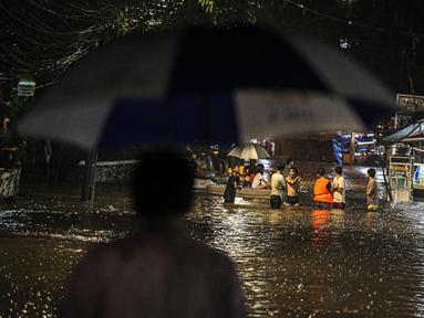 Sejumlah warga melintasi genangan banjir di kawasan Kemang, Jakarta, Selasa (4/10/2022). Jalan Kemang Utara IX tak bisa dilalui oleh kendaraan. Banjir menggenangi kawasan Pasar Kambing dan sejumlah rumah penduduk. (Liputan6.com/Faizal Fanani)