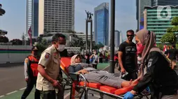 Petugas Dinas Kesehatan DKI Jakarta melakukan evakuasi kepada seorang warga yang mengalami pendarahan karena kelelahan saat CFD di Kawasan Bundaran HI, Jakarta, Minggu (14/8/2022). Warga tersebut langsung mendapatkan penanganan medis dan di bawa ke rumah sakit terdekat. (Liputan6.com/Angga Yuniar)