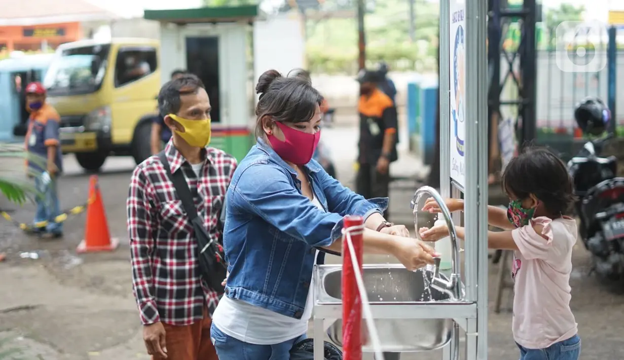 Pengunjung mencuci tangan saat masuk ke kawasan Pasar Minggu, Jakarta, Selasa (23/6/2020). Pascapenutupan tiga hari terkait ditemukannya tiga pedagang yang positif COVID-19, pengunjung Pasar Minggu kini diwajibkan mencuci tangan dan cek suhu tubuh. (Liputan6.com/Immanuel Antonius)