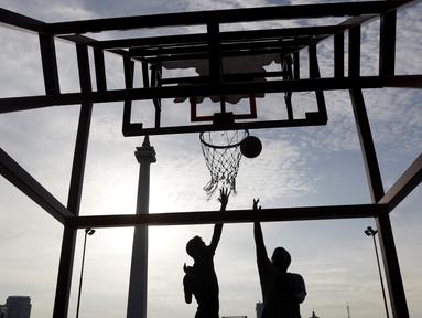 Dua orang warga berusaha memasukan bola saat olahraga basket di Kawasan Monumen Nasional, Jakarta, Rabu (13/2). Monas merupakan salah satu lokasi yang kerap dijadikan ruang olahraga bagi warga ibukota. (Bola.com/M. Iqbal Ichsan)