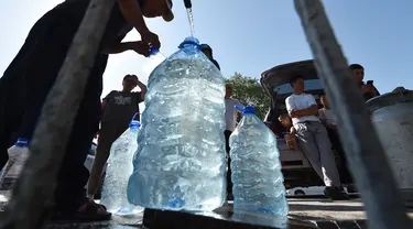 Warga Kyrgyz mengambil air dari mata air artesis di sebuah masjid dekat distrik Archa-Beshik di ibu kota Bishkek pada 8 Juni 2023. Penduduk ibu kota Kyrgyz berkumpul di sekitar lubang bor dengan botol plastik, satu-satunya cara bagi mereka untuk mendapatkan air setelahnya awal musim panas yang kering. (VYACHESLAV OSELEDKO / AFP)