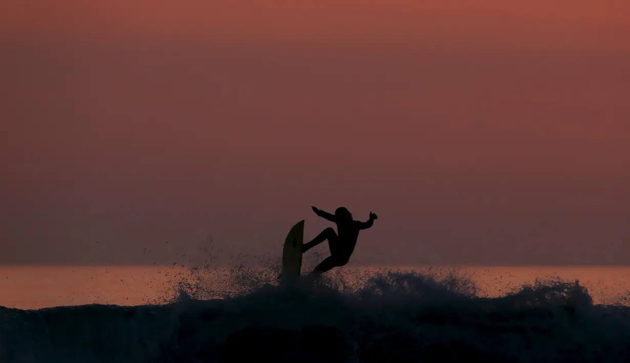 Peselancar menjajal ombak saat matahari terbenam di sebuah pantai di La Serena, Chile, Selasa (23/5/2015). (REUTERS/Marcos Brindicci)