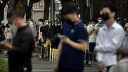 Orang-orang yang mengenakan masker mengantre untuk tes virus corona COVID-19 di tempat pengujian pada hari ketiga pengujian massal untuk jutaan penduduk di Distrik Chaoyang, Beijing, China, 15 Juni 2022. (AP Photo/Mark Schiefelbein)