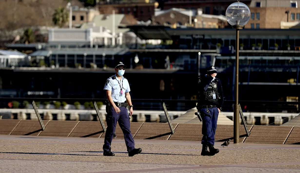 Polisi berpatroli di sekitar Gedung Opera, Sydney, Australia, Selasa (13/7/2021). Lima juta penduduk Sydney akan berada dalam lockdown COVID-19 untuk dua minggu lagi. (Brendon THORNE/AFP)