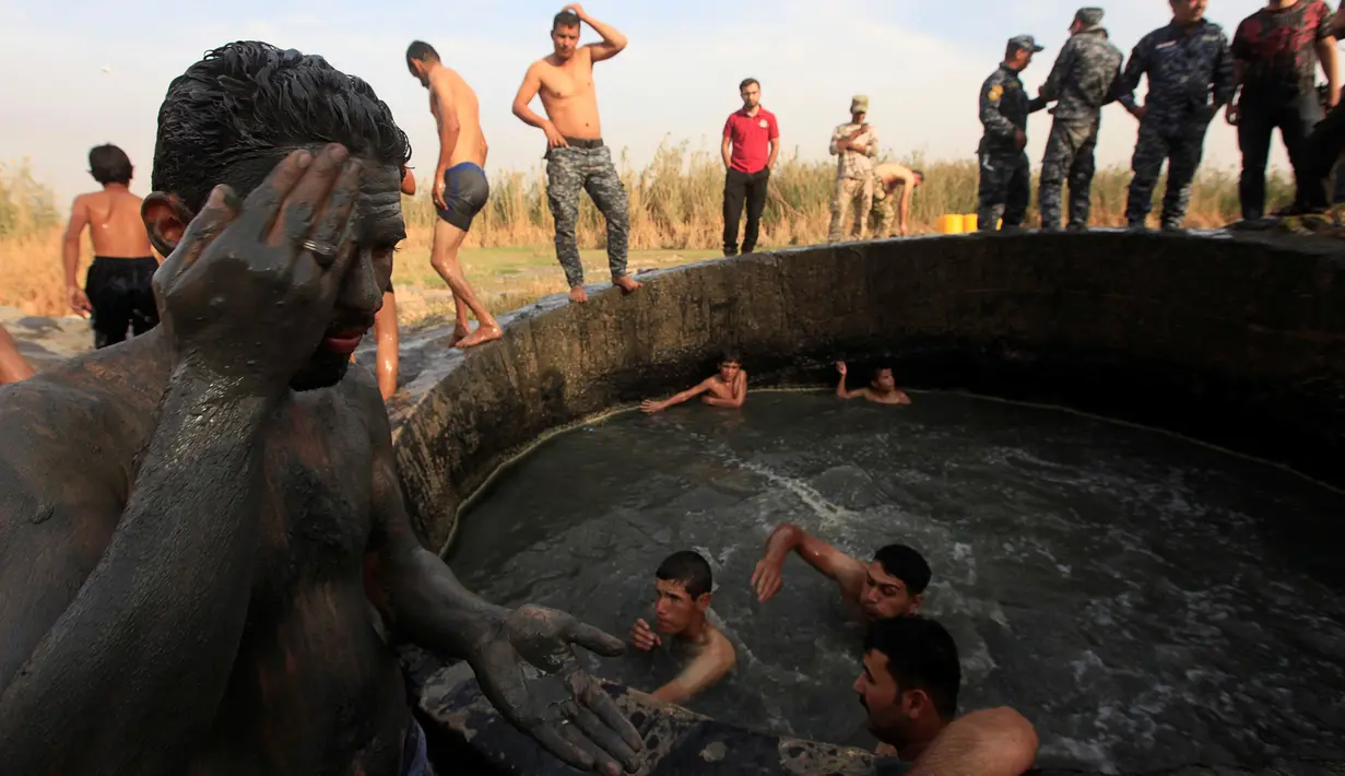 Seorang tentara Irak melumuri wajahnya dengan belerang di Hammam al-Ali, Mosul, Irak, (9/11). Di tengah perang melawan ISIS, mereka melepaskan penat dan lelah dengan berenang di Kolam belerang. (REUTERS/Alaa Al-Marjani)