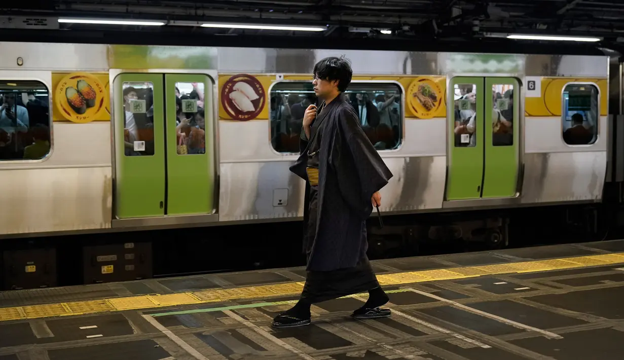 Seorang pria yang mengenakan kimono tradisional berjalan melewati kereta Yamanote Line yang penuh sesak di Stasiun Shinjuku di Tokyo, Jepang, Sabtu (25/5/2019). (AP Photo/Jae C. Hong)