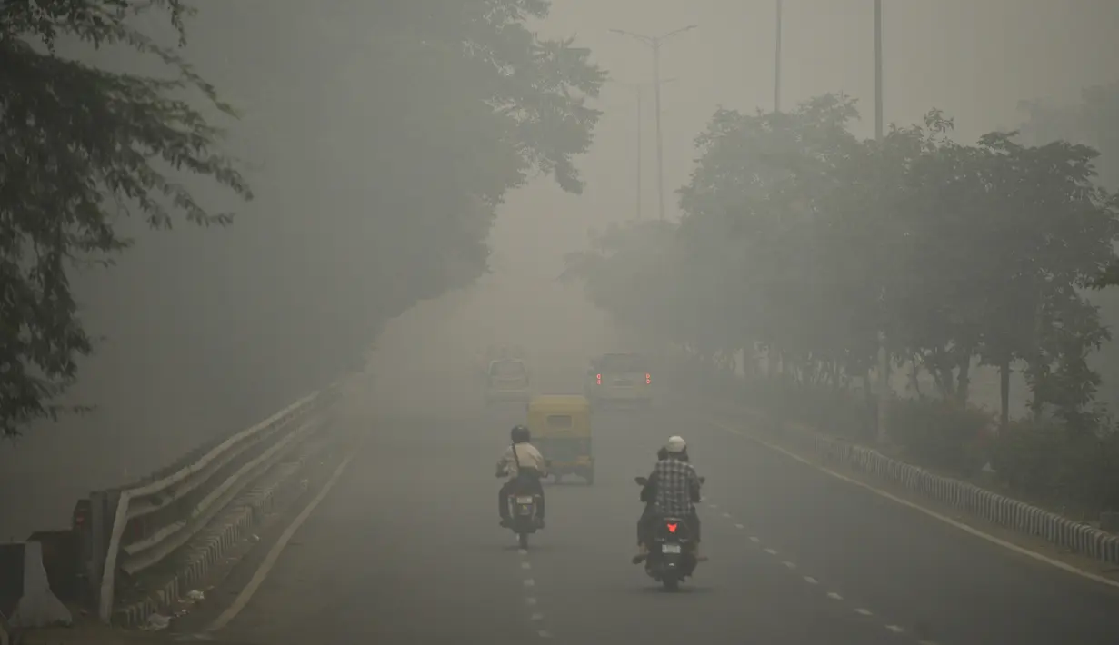 Kendaraan bermotor menembus kabut asap pekat yang menyelimuti jalan di New Delhi, Minggu (3/10/2019). Polusi di New Delhi disebabkan asap kembang api dalam Festival Diwali dan kabut asap akibat pembukaan lahan di pinggiran kota dan negara bagian di sekitarnya. (Photo by Sajjad  HUSSAIN / AFP)