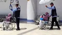 Petugas haji memayungi jemaah haji lansia yang baru tiba di Bandara Prince Mohammed bin Abdulaziz Madinah via jalur fast track. (dok. Dinny Mutiah/MCH 2025)