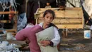 Seorang anak membawa barang-barang yang bisa diselamatkan setelah serangan udara Israel pada malam sebelumnya di kamp pengungsi Bureij di Jalur Gaza tengah pada 8 Oktober 2024. (Eyad BABA/AFP)