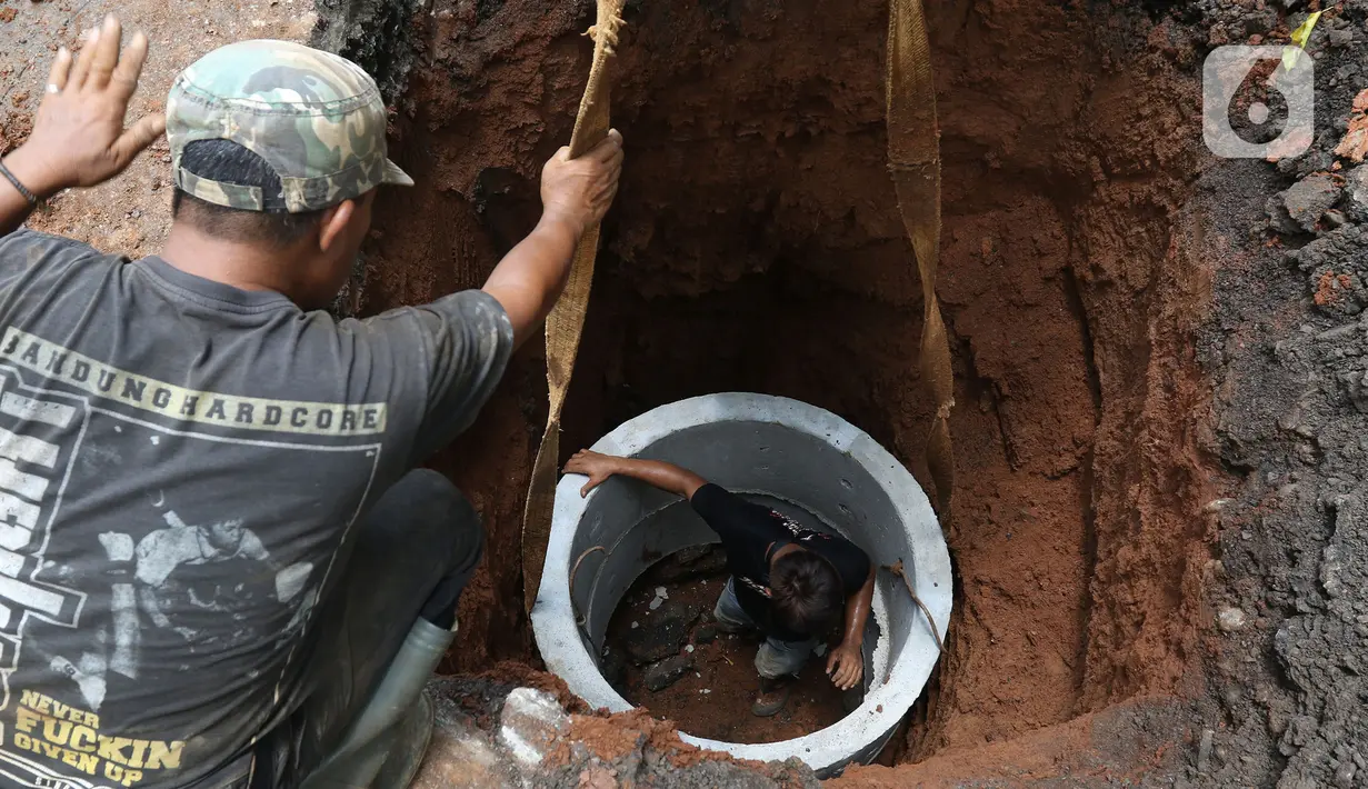 Pekerja sedang menyelesaikan pengerjaan sumur resapan di Jalan Mataram Raya, Kebayoran Baru, Jakarta, Selasa (12/10/2021). Pemerintah Provinsi (Pemprov) DKI Jakarta tengah mempercepat pembangunan sumur resapan yang ditargetkan terbangun di 22.292 titik. (Liputan6.com/Herman Zakharia)