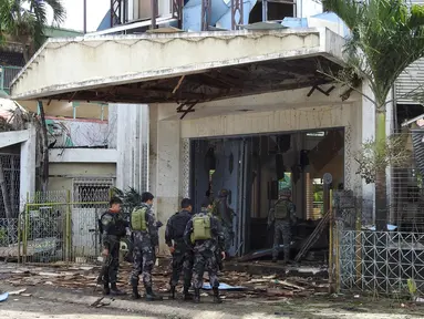 Polisi dan tentara berjaga pasca ledakan bom di Gereja Katolik Jolo, Filipina Selatan, Minggu (27/1). Dua bom meledak, Sedikitnya 27 orang tewas dan 57 orang lainnya mengalami luka. (Nickee Butlangan/AFP)