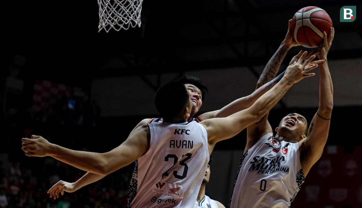 Pemain Pelita Jaya, Vincent Kosasih (tengah) berebut bola dengan pemain Satria Muda, Juan Laurent Kokodiputra (kanan) dan Avan Seputra (kiri) pada laga gim ketiga final IBL All Indonesia 2024 yang berlangsung di Hall Basket, Senayan, Jakarta, Sabtu (06/10/2024). Pelita Jaya menang dengan skor 75-70. (Bola.com/Bagaskara Lazuardi)
