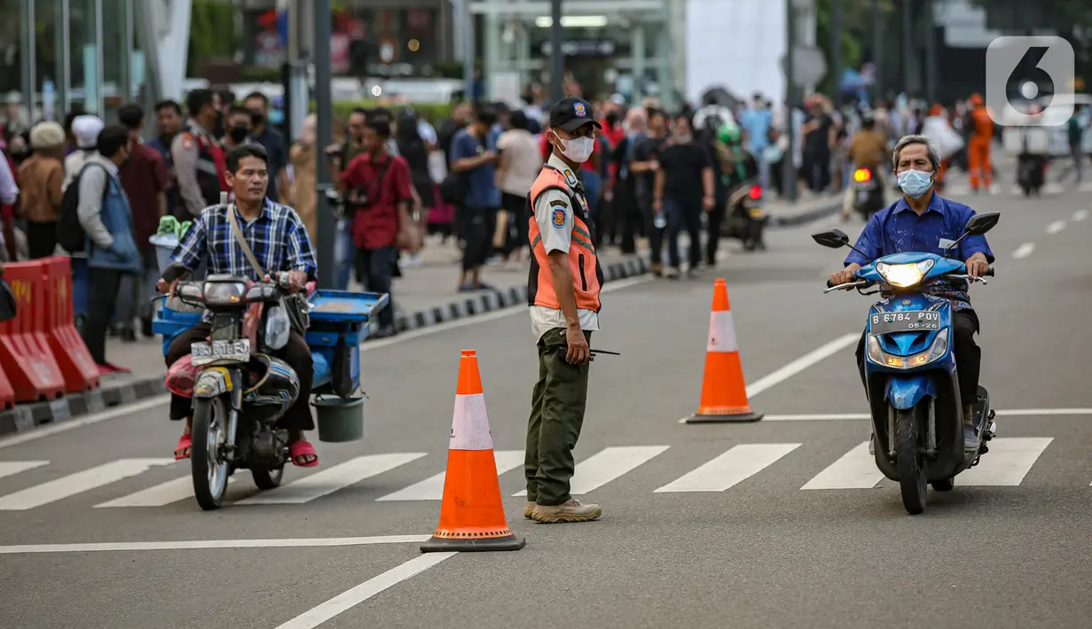 Personel gabungan dari unsur polisi hingga Satpol PP mengatur lalu lintas di kawasan zebra cross Dukuh Atas, Jakarta, Rabu (27/7/2022). Mereka dikerahkan untuk memantau kegiatan peragaan busana Citayam Fashion Week (CFW) guna meminimalisir terjadinya kriminalitas, kemacetan, hingga parkir liar. (Liputan6.com/Faizal Fanani)