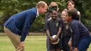 Pangeran William berbincang dengan anak-anak program pendidikan sepak bola Wildcats Girls saat mengunjungi tim sepak bola wanita Inggris, di Kensington Palace, London, Kamis (13/7). (Dominic Lipinski / POOL / AFP)