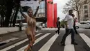 Pejalan kaki melihat aksi Sabrina Boing Boing dari sekolah Samba Tautape berjalan memegang poster bertuliskan "Juara" di Jalan Paulista, Sao Paulo, Brasil (2/3). Untuk pertam kalinya sejak 64 tahun sekolah Samba ini menang. (AFP Photo / Nelson Almeida)