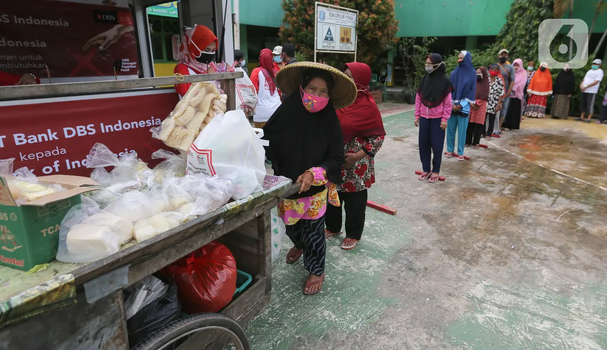 Warga terdampak Covid-19 antre mendapatkan paket makanan di Cipulir, Jakarta Jumat (18/12/2020). Bantuan langsung kepada 8.000 kepala keluarga disalurkan melalui Foodbank of Indonesia (FOI) sebagai kelanjutan dari kampanye “DBS Stronger Together Fund”. (Liputan6.com/Fery Pradolo)