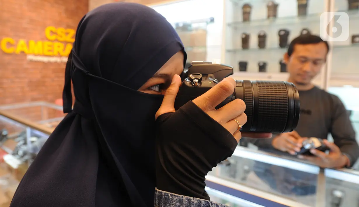 Calon pembeli mencoba kamera bekas  yang dijual belikan di CSZ Camera di kawasan Pondok jagung, Tangerang Selatan, Banten, Senin (20/12/2021). Di masa pandemi penjualan kamera bekas meningkat 30 persen. (merdeka.com/Arie Basuki)