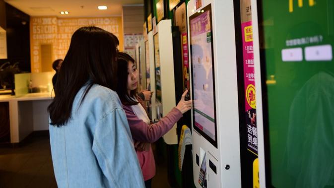 Gambar ini diambil pada 11 April 2018, menunjukkan pelanggan yang memasukkan pesanan dengan mesin pembayaran di restoran McDonald di Beijing. ( Wang Zhao / AFP.