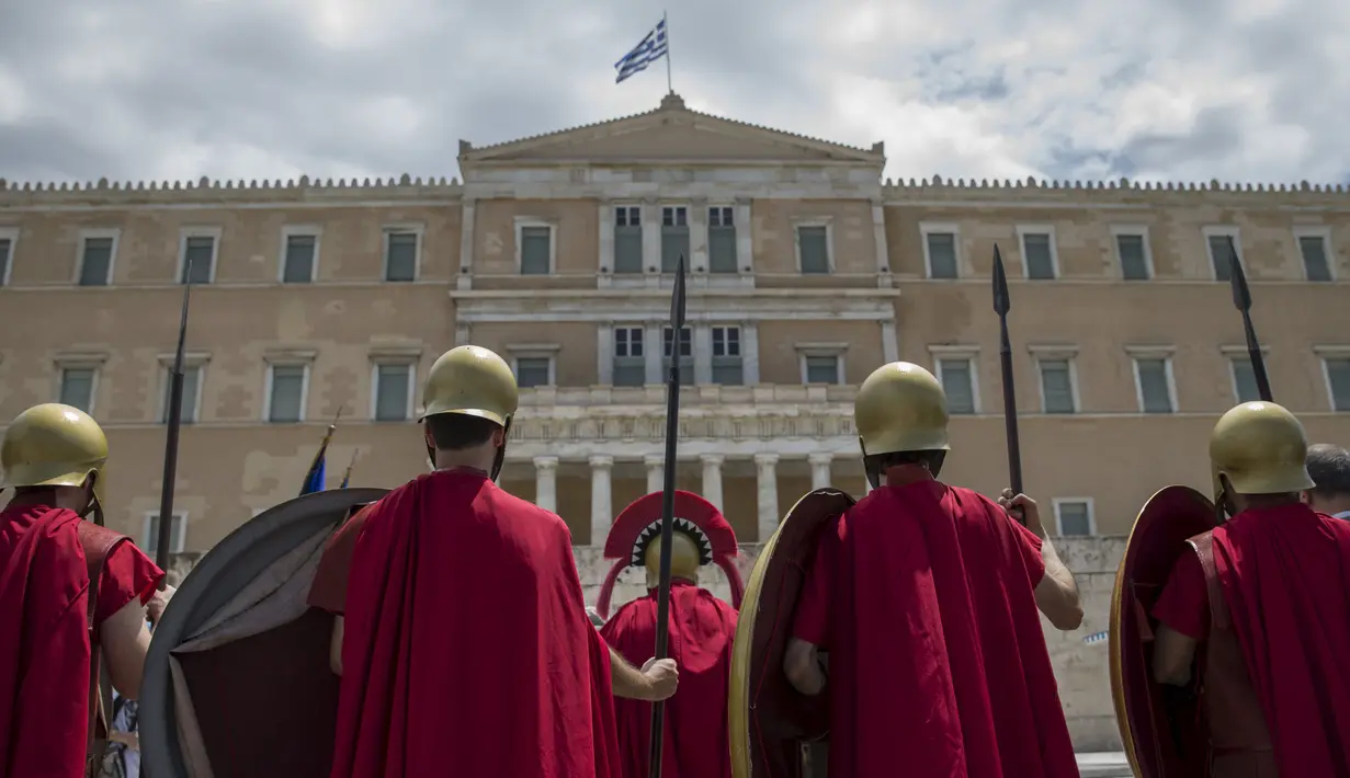 Para pria menggunakan pakaian tentara Yunani kuno, berdiri di depang gedung parlemen dengan membawa tombak dan tameng, Athena, Yunani (21/6/2015). (REUTERS /Marko Djurica)