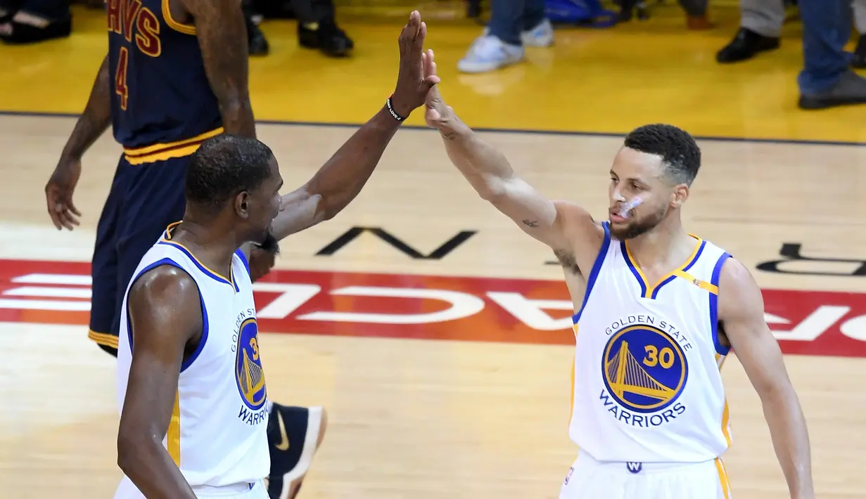 Pemain Golden State Warriors Kevin Durant (35) dan Stephen Curry (30) melakukan selebrasi saat bertanding melawan Cleveland Cavaliers di gim pertama Final NBA 2017 di Oracle Arena di Oakland, California (1/6). (Thearon W. Henderson/Getty Images/AFP)