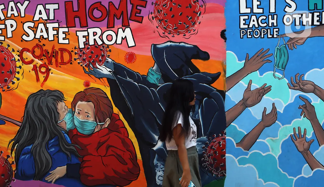 Warga berjalan di depan mural bertema virus corona COVID-19 yang menghiasi dinding rumah di kawasan Pangkalan Jati Baru, Depok, Jawa Barat, Selasa (2/6/2020). Mural bertulis ‘Stay At Home, Keep Safe From COVID-19’ itu untuk mengingatkan warga akan bahaya COVID-19. (Liputan6.com/Johan Tallo)